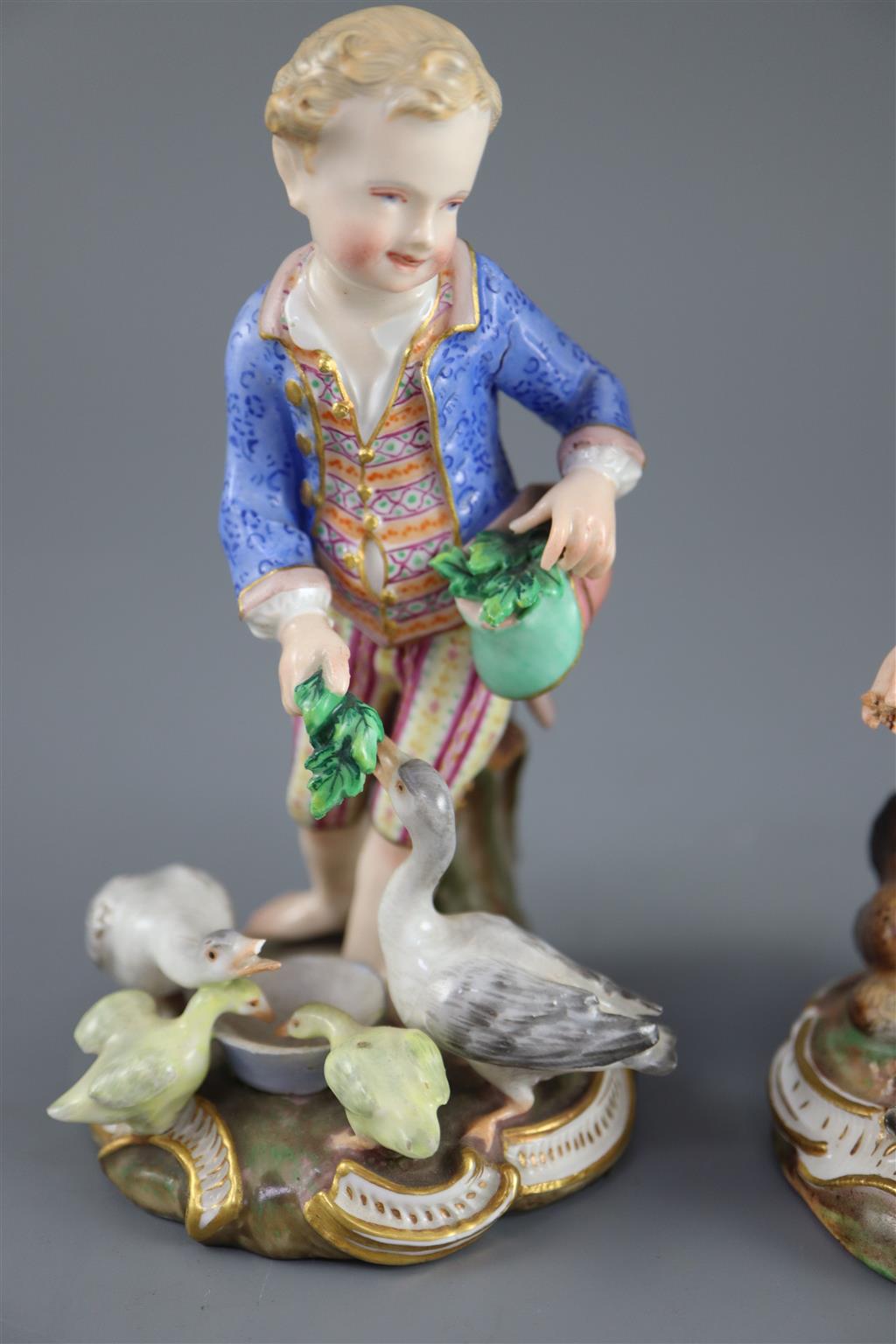 A pair of Meissen figures after the 18th century models of children feeding geese and chickens, 19th century, 12cm and 13cm high
